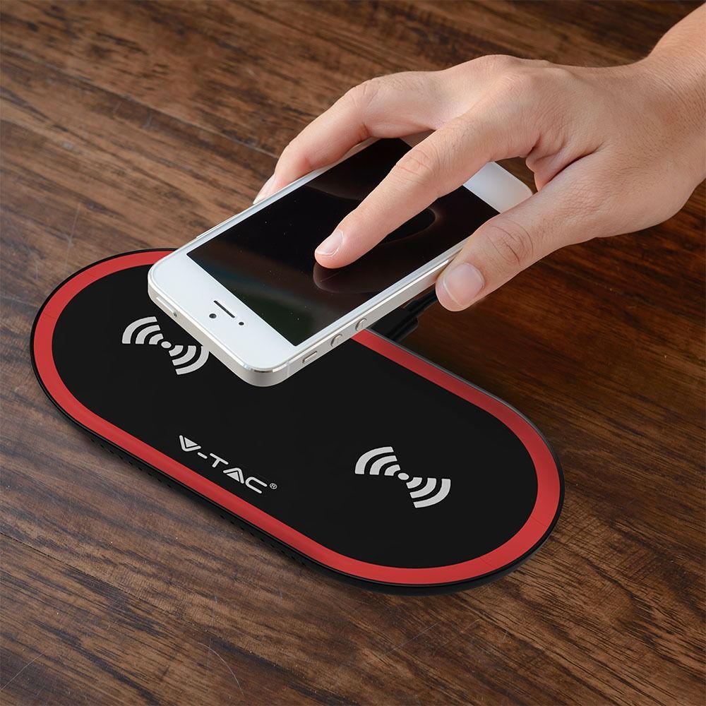 Person placing an IPhone on a smart wireless charger for 2 phones